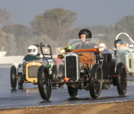 Not letting the wet stop her, Michelle is coming down the inside of a Singer 10 Triple S and a GN Vitesse Special into Turn 1 at Historic Winton